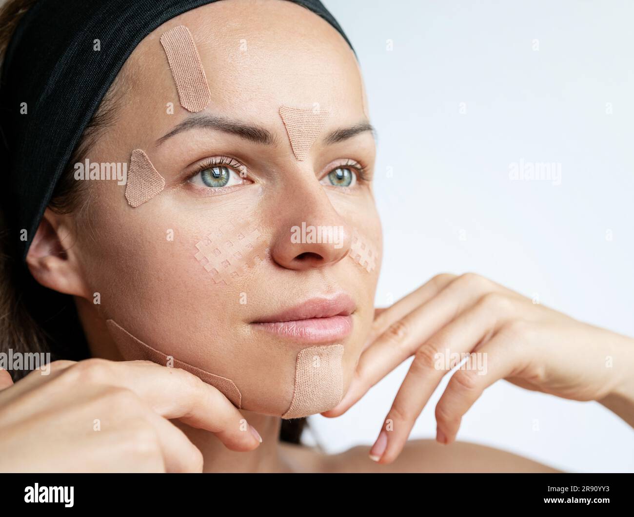 Female face with kinesio tapes for the face close-up. Beauty, lifting
