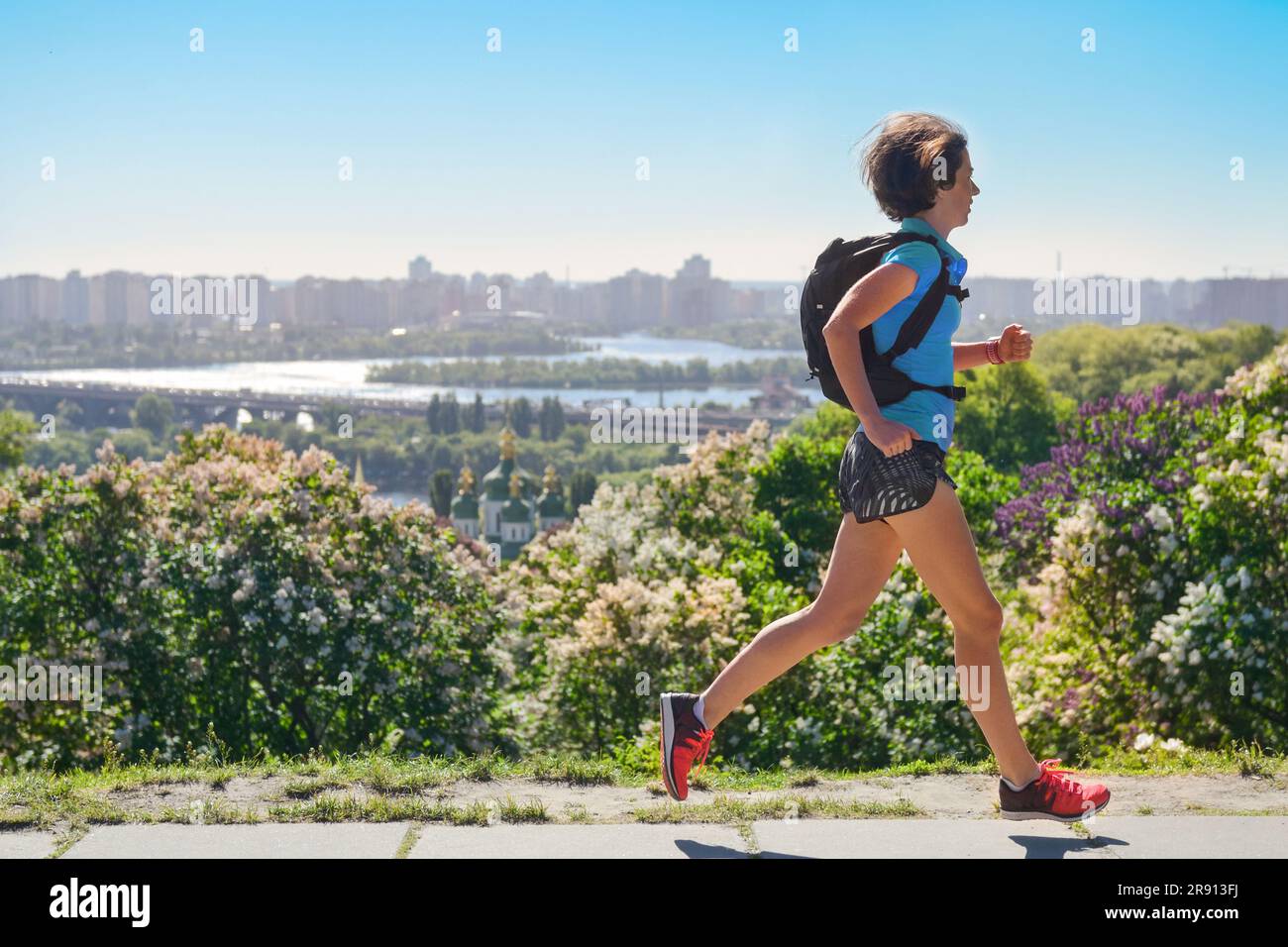 Active woman runner run commutes to work with backpack, city morning run commuting and healthy lifestyle concept, skyline of Kyiv, Ukraine Stock Photo
