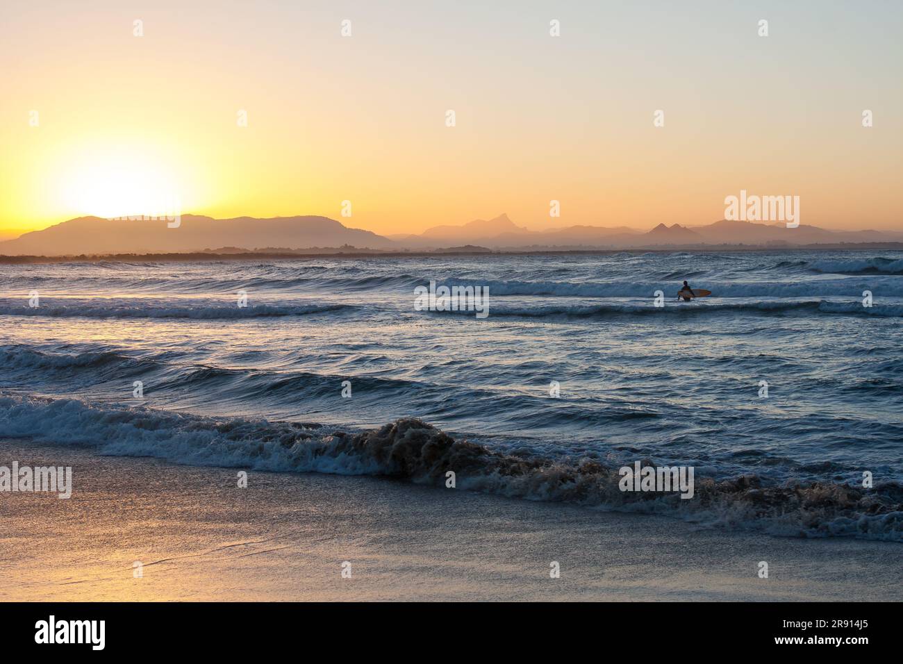 Lone surfer in the water in Byron Bay, Australia at sunset. Stock Photo