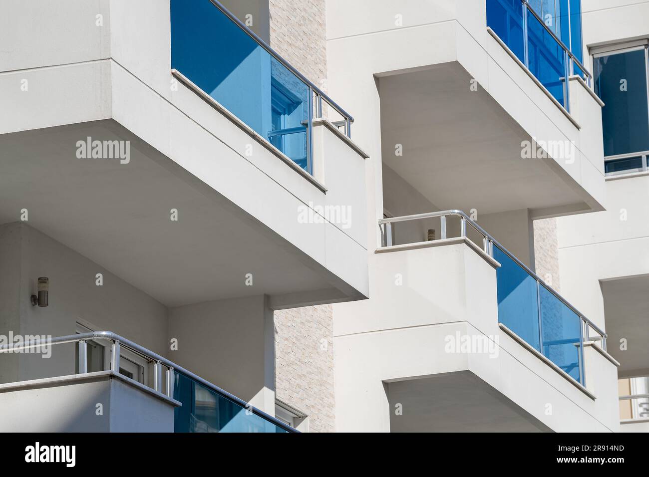 Part of a white building. Square balconies with metal railings Stock