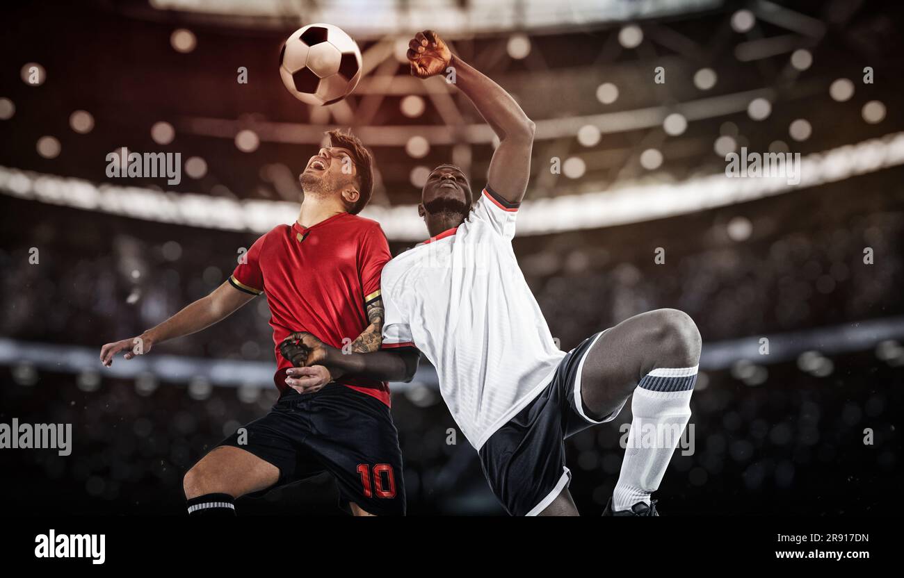 Football action with competing soccer players jumping to hit the ball with head Stock Photo Alamy