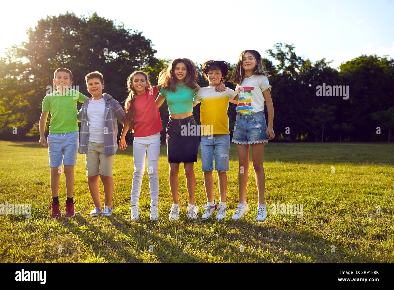 Kids school friends boys and girls resting in nature on sunny days standing side by side in park Stock Photo