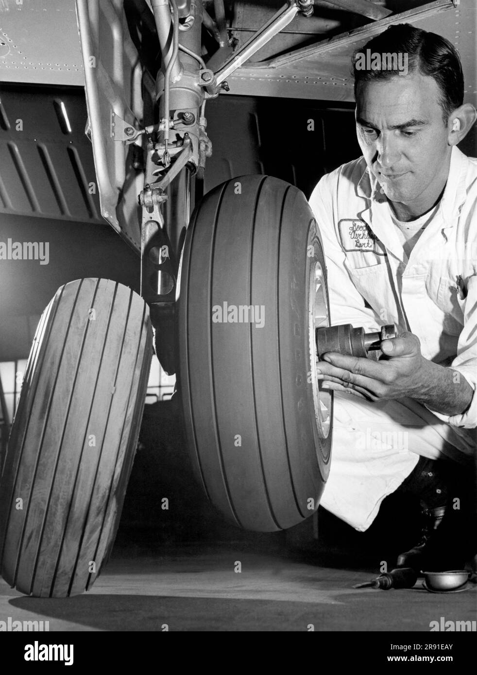 Akron,  Ohio:  c. 1967. An aircraft mechanic changes the old tire for one of Goodyear's new wide rib tires that puts more rubber on the ground and improves tread wear. Stock Photo