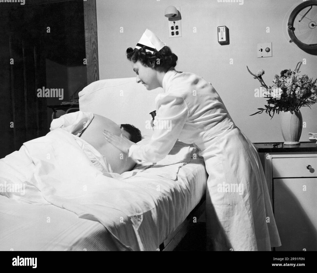 United States:  July 23, 1942. A Navy Medical Corps nurse gives a post-op sailor a rub down to relieve sore and stiff muscles. Stock Photo