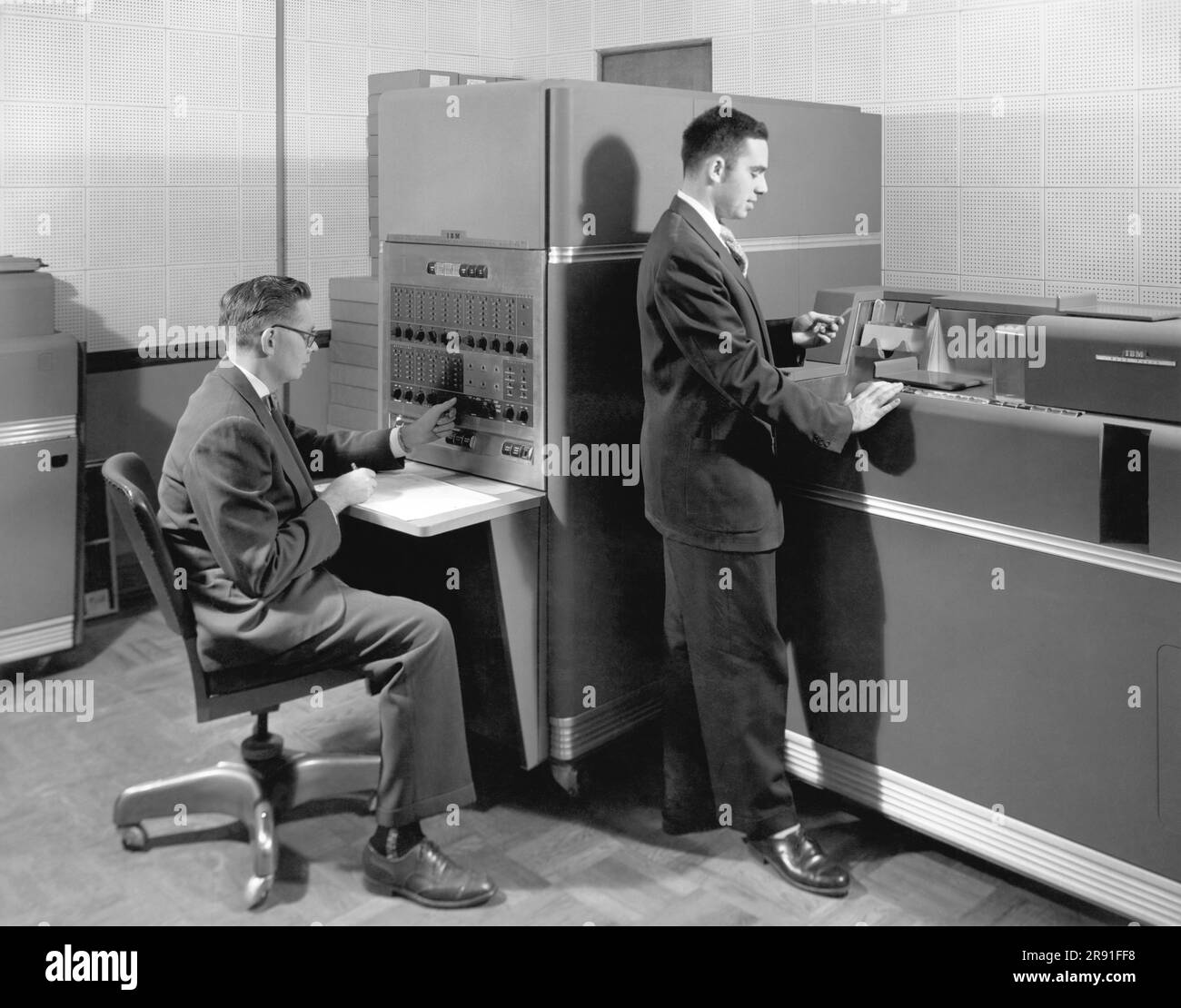 United States:  c. 1954 Two men in an office using an IBM 650 Magnetic Drum Data Processing Machine with punch cards. Stock Photo