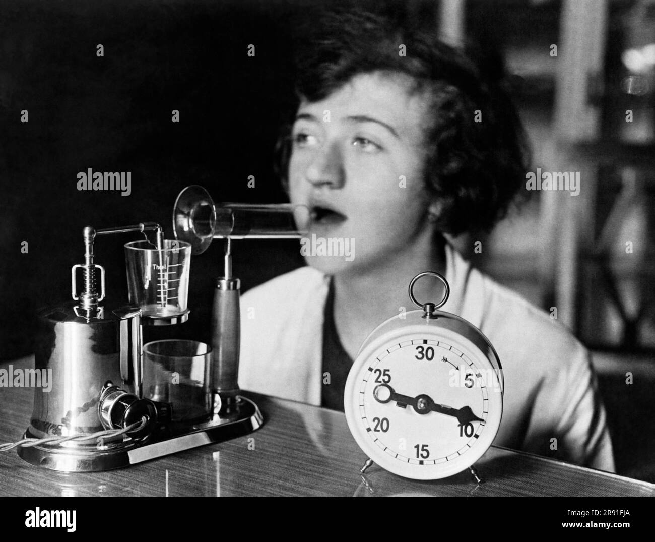 United States:  c. 1929 A woman using an electric inhaling apparatus which produces a medicated fog used in the treatment of colds and influenza. Stock Photo