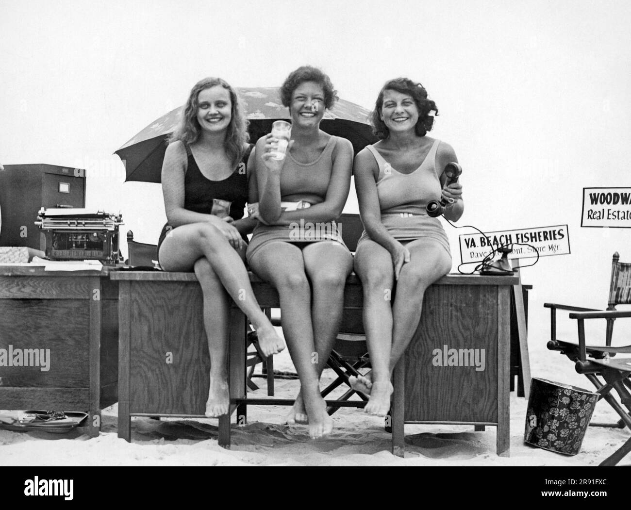 Virginia Beach, Virginia:  c. 1928. Three Virginia Beach executives decided to move their entire office staffs to the seashore for a few days during a heat wave. Most clients arrived in the usual business clothes, while bathing suits were the proper attire of the office force. Here are three of the executive secretaries just before taking a dip during the lunch period. Stock Photo