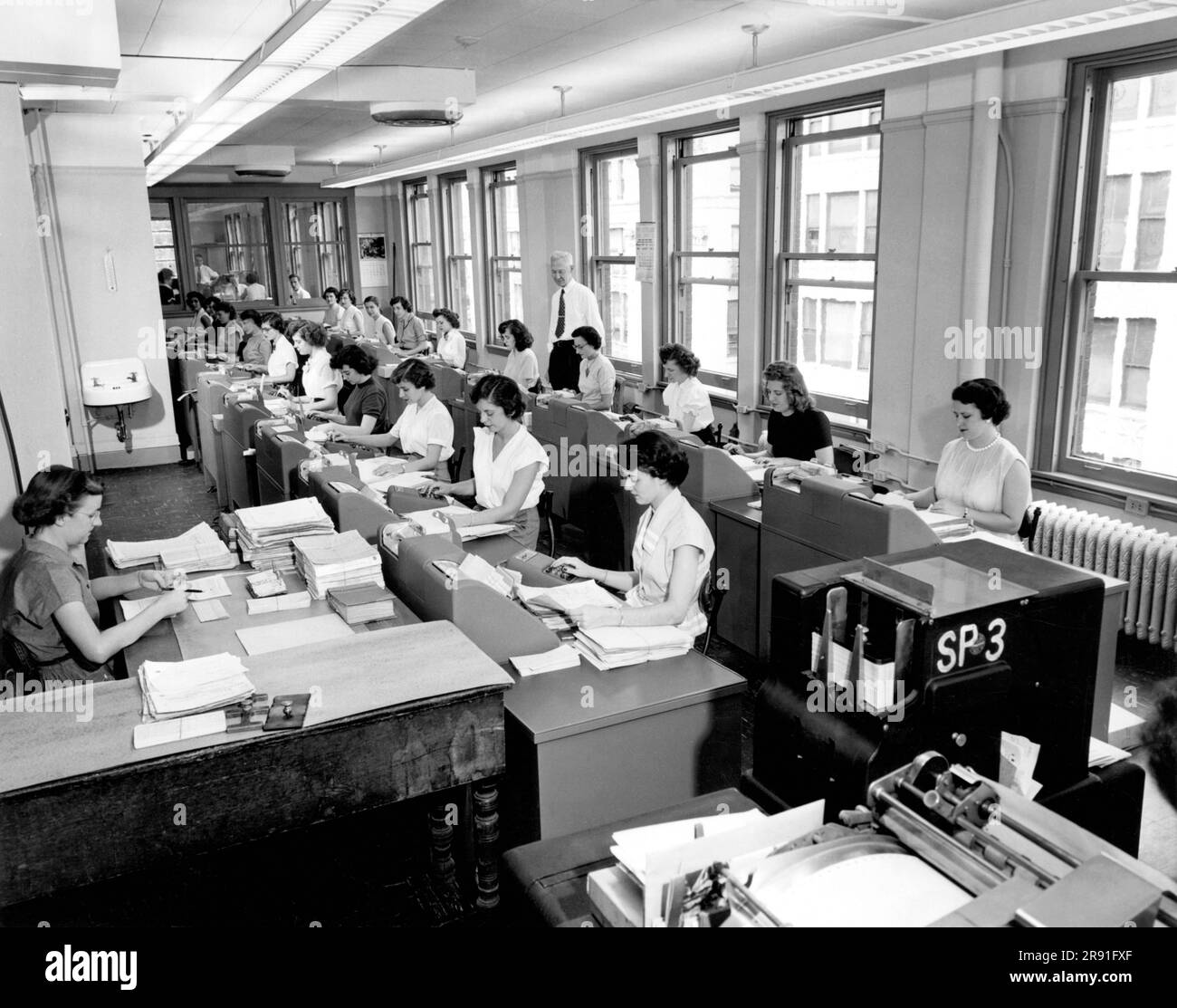 Cleveland, Ohio:  c. 1960 Rows of women office workers entering data using keypads and punch cards at the Erie Railroad offices. Stock Photo