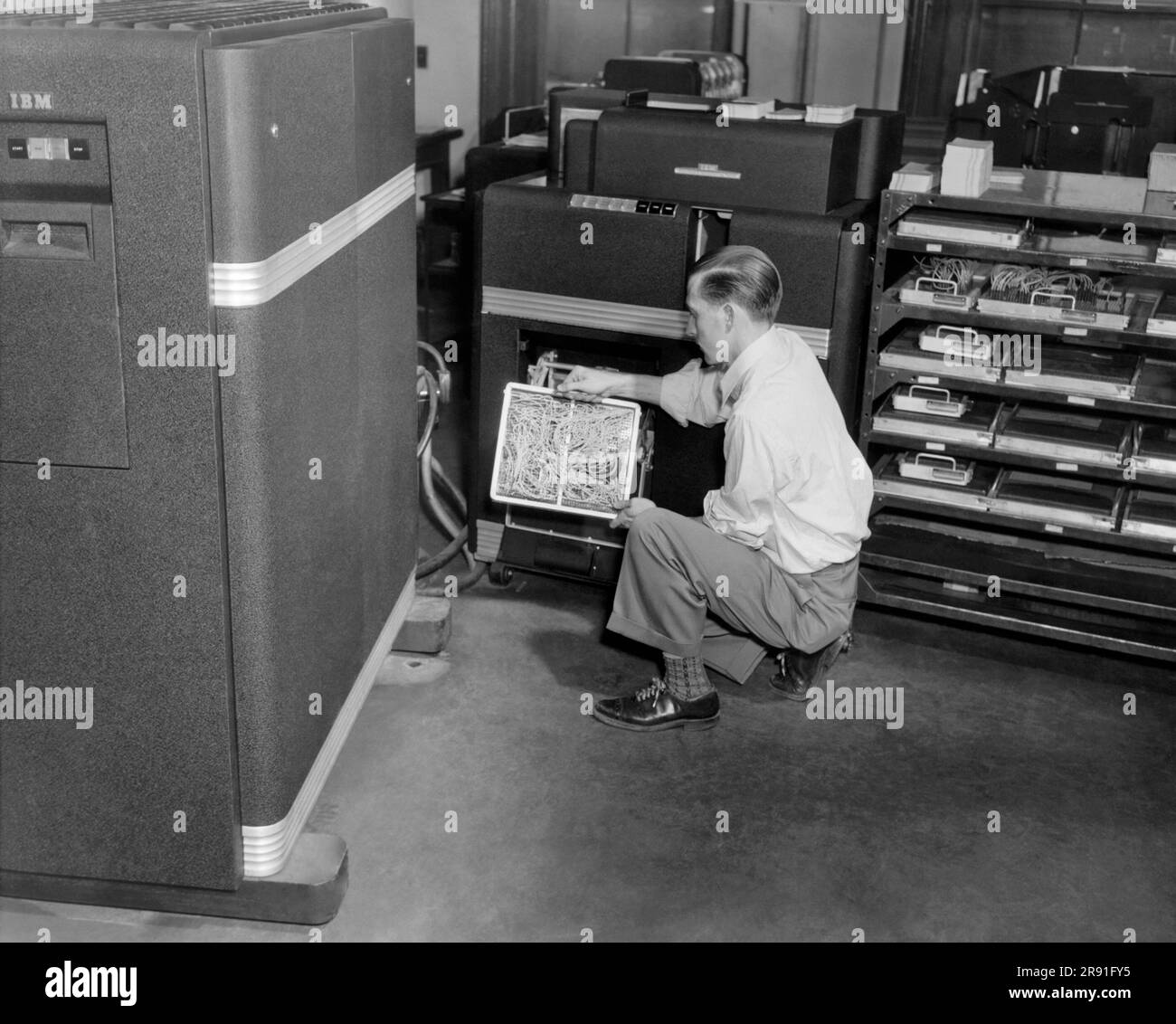 Cleveland, Ohio:  c. 1952 A computer technician holding a wired circuit board installed in an IBM punch card machine. Stock Photo