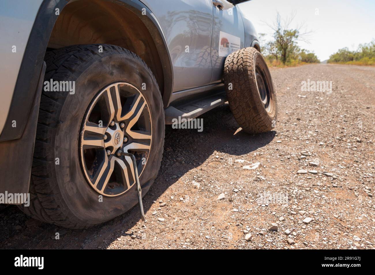 A 4x4 car with a flat tyre has the spare tyre ready to replace it on the Gibb River Road in Western Australia Stock Photo