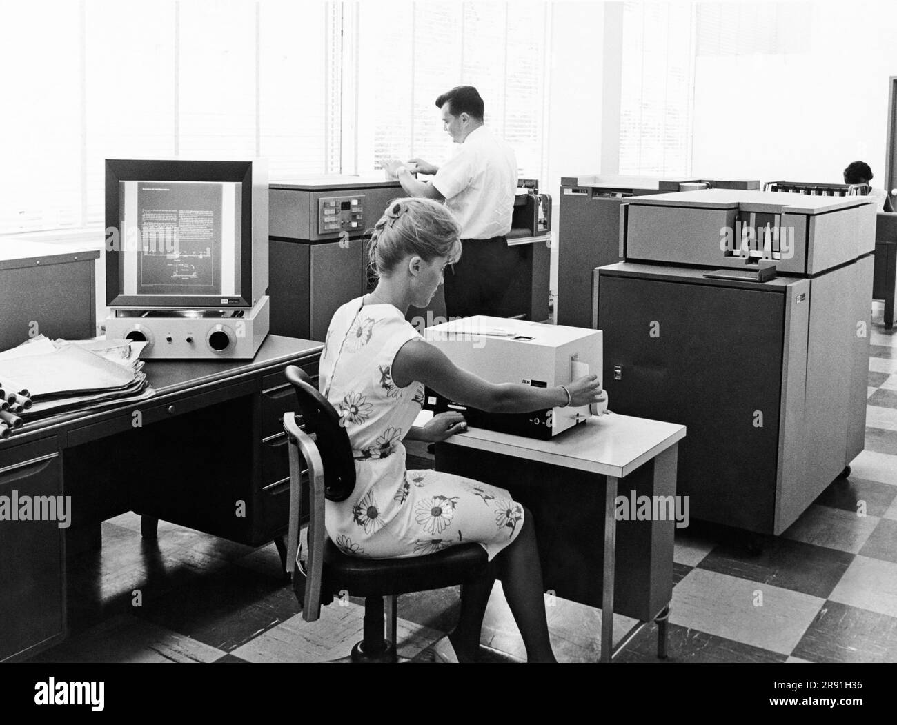 White Plains, New York:  August 4, 1966 Workers at the IBM Film Conversion Center convert up to 90 original documents into a single microfiche sheet, of which one frame is projected on the IBM Document Viewer at left or into aperture cards such as those coming out of the Micro-Copier. Stock Photo