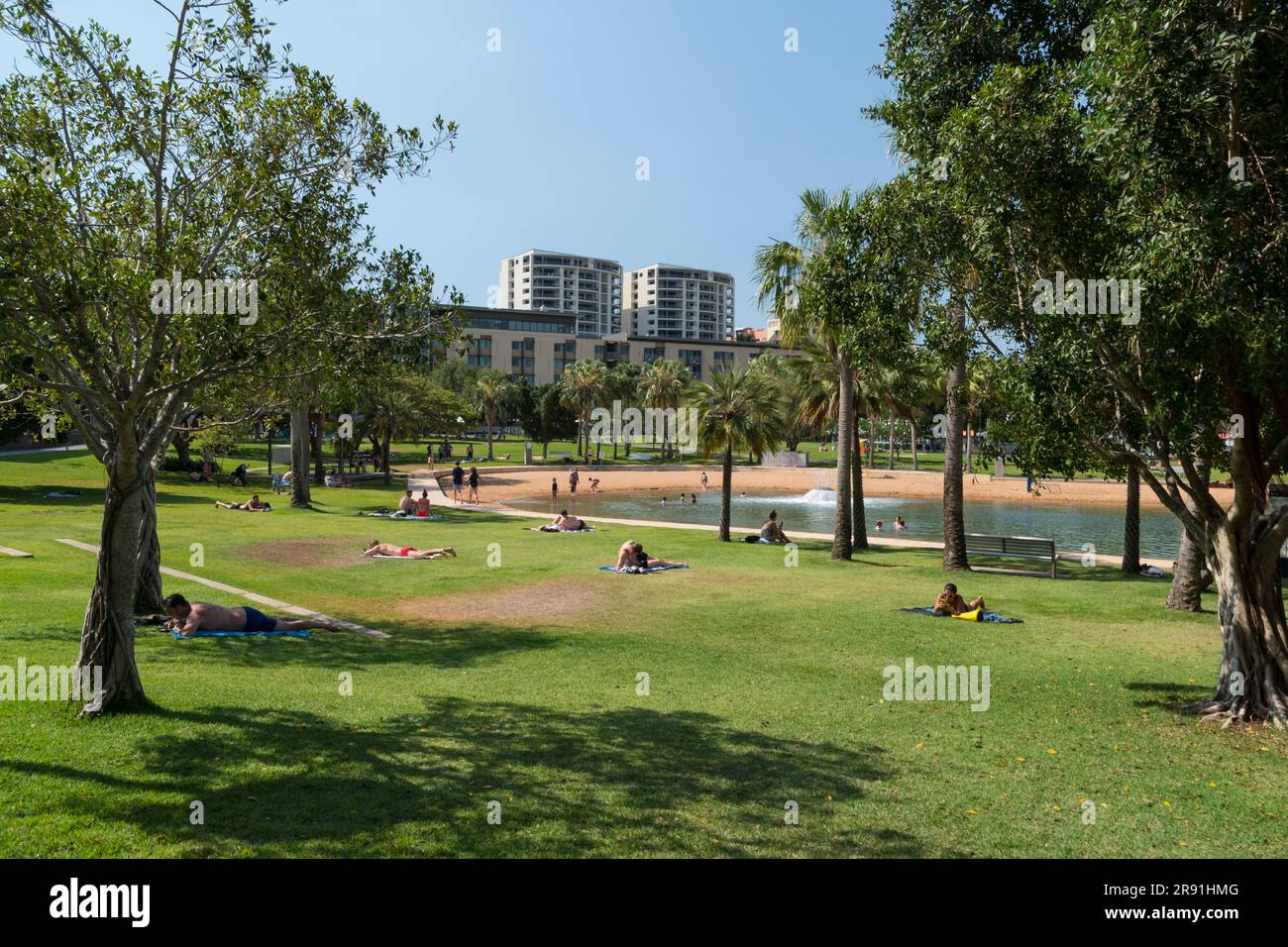 People relax in the sun on the grass in Darwin Waterfront Precinct in the Northern Territory in Australia Stock Photo