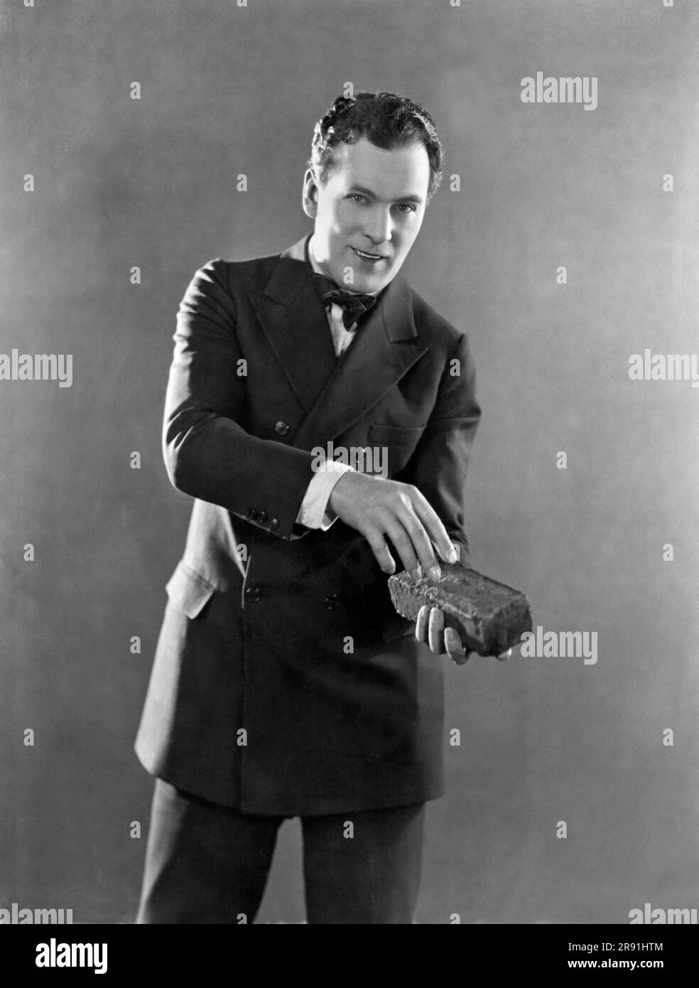 Hollywood, California:   1924. Actor Thomas Meighan holding a brick in his latest film, 'The Confidence Man' Stock Photo
