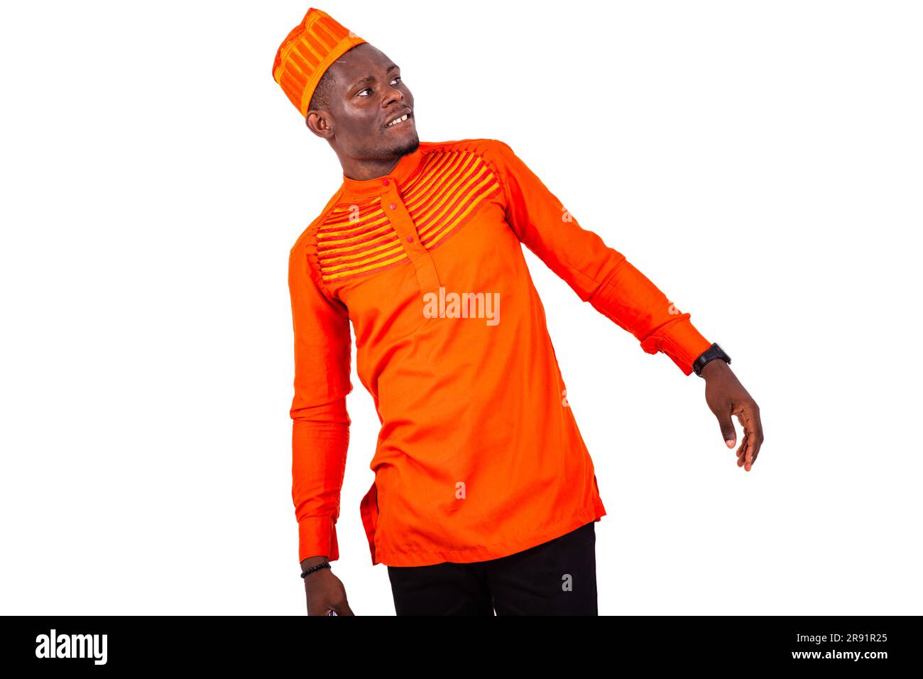 a handsome businessman in orange clothes standing against white background and leaning to look at something smiling Stock Photo
