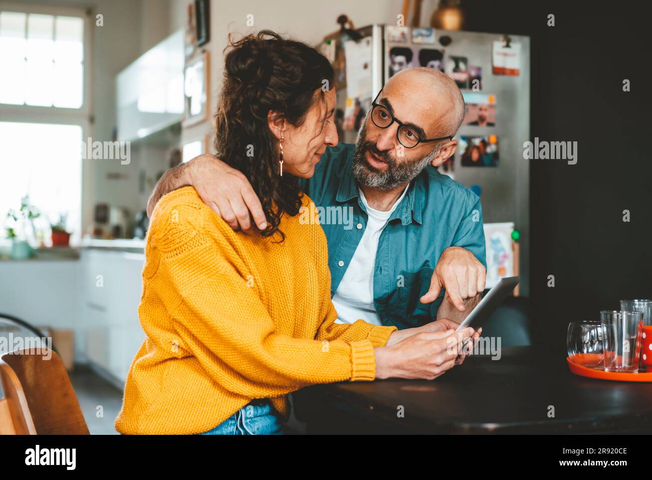 Man pointing at tablet PC held by woman sitting at home Stock Photo