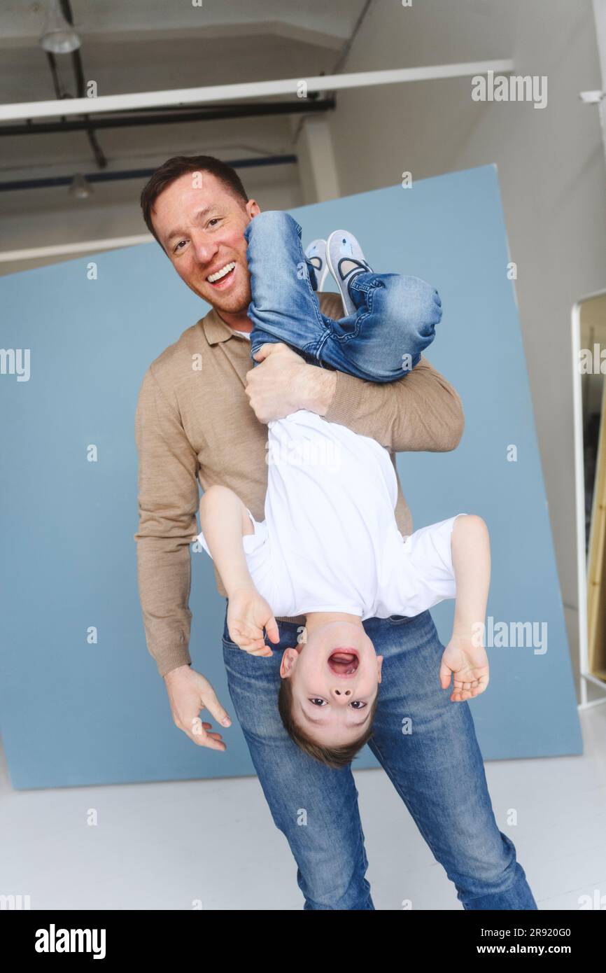 Happy father holding son in upside down position Stock Photo