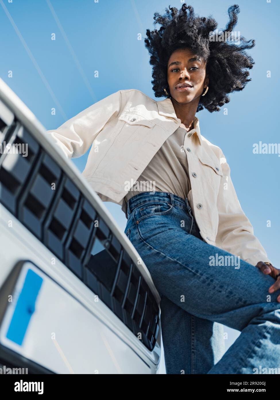 Young woman sitting on car hood in front of sky Stock Photo Alamy