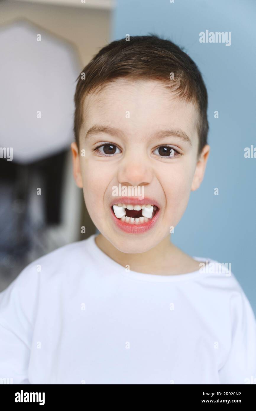 Boy holding marshmallows between teeth Stock Photo Alamy