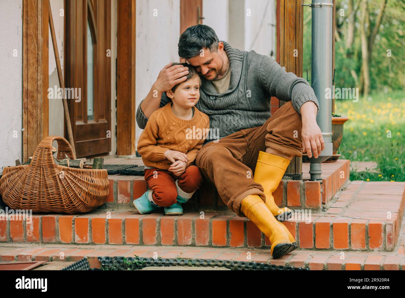 Father embracing son sitting on steps of house Stock Photo - Alamy