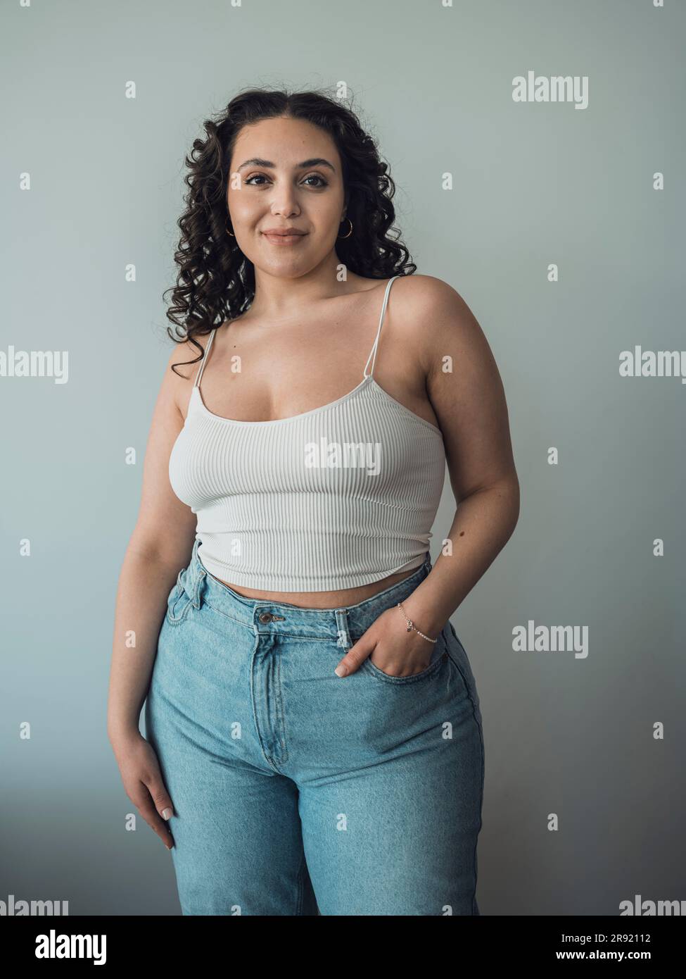 Curvy woman with hand in pocket standing in front of wall Stock Photo -  Alamy