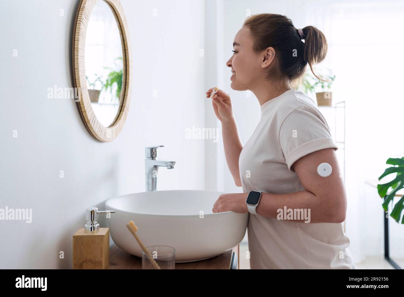Woman with diabetes brushing teeth in bathroom at home Stock Photo