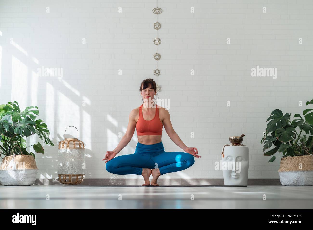 Woman practicing Lotus position in front of wall Stock Photo