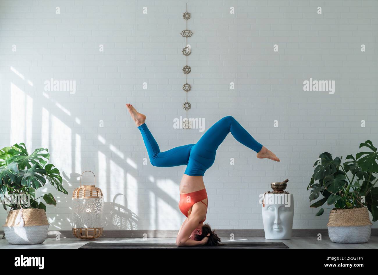 Woman doing supported headstand pose in front of wall Stock Photo