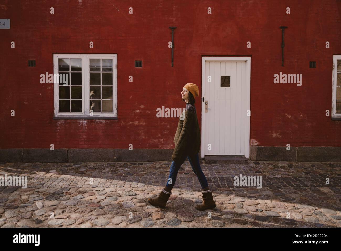 Woman walking on cobblestone street by building Stock Photo