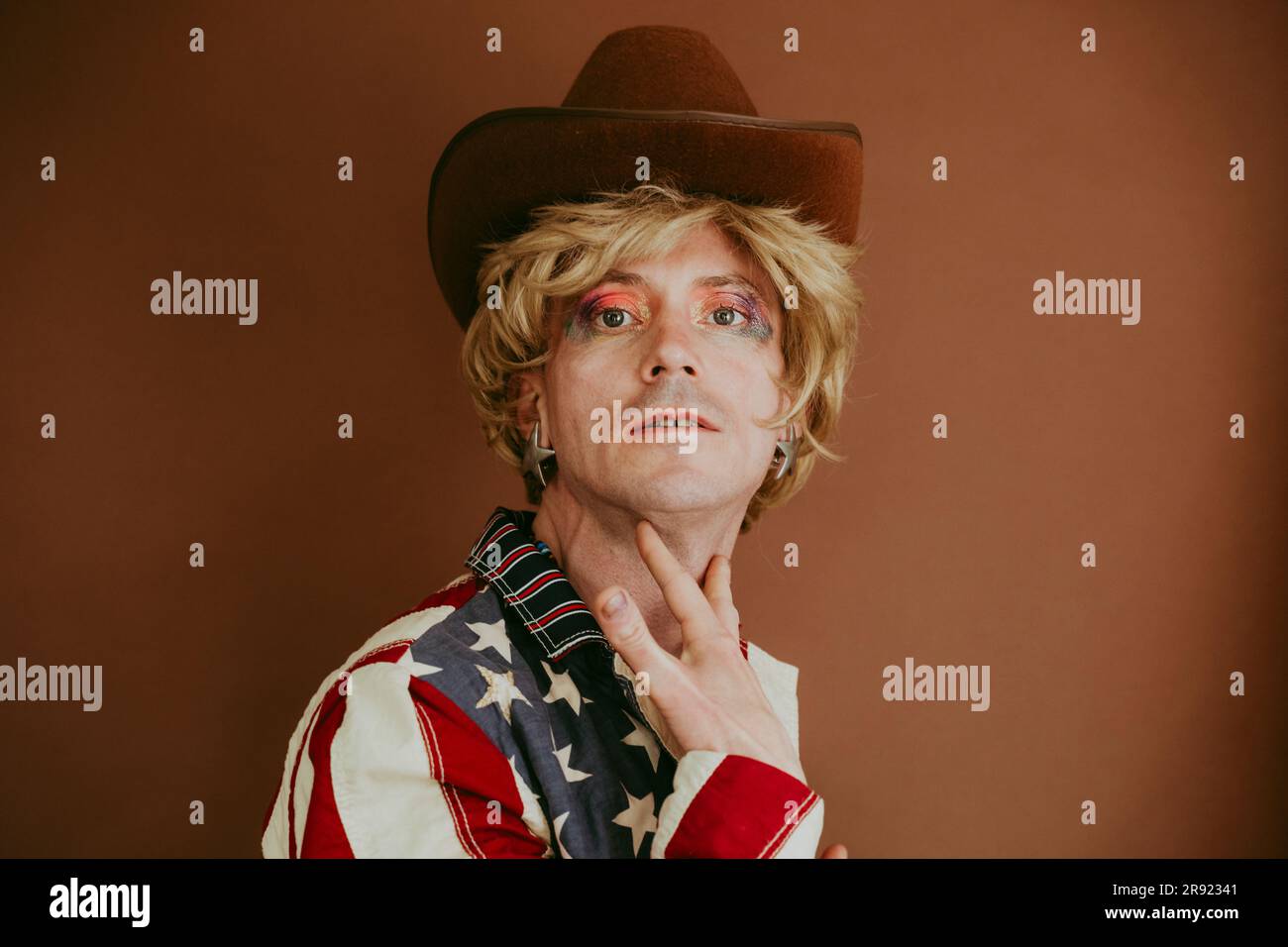 Drag queen wearing hat against brown background Stock Photo - Alamy
