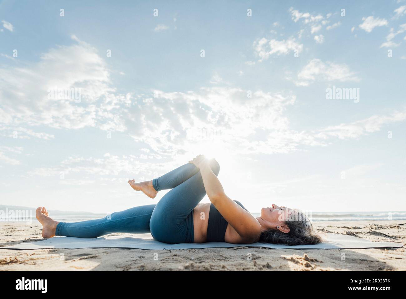 Woman stretching leg lying down exercise mat beach hi-res stock ...