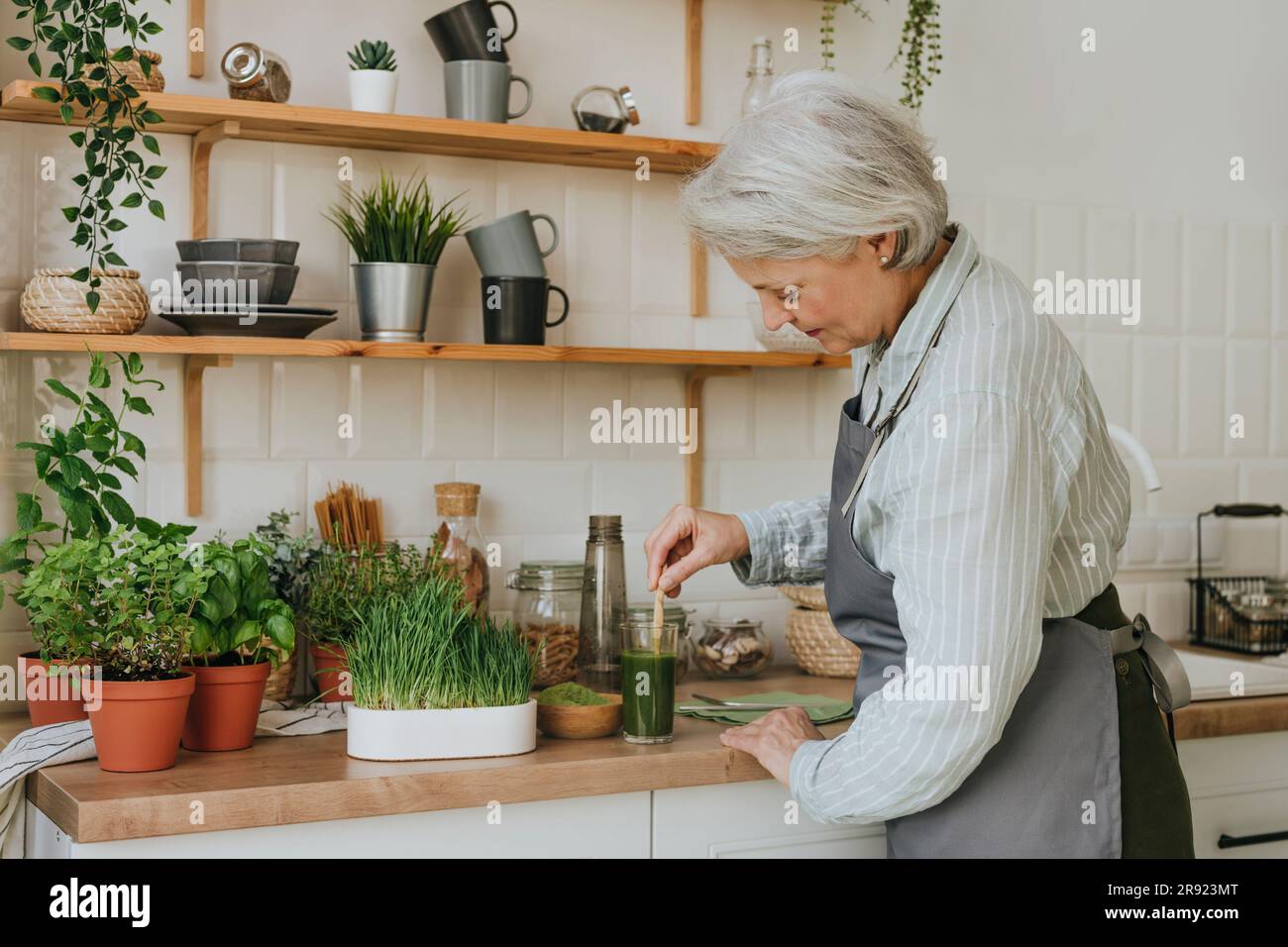 Woman preparing detox juice in kitchen at home Stock Photo