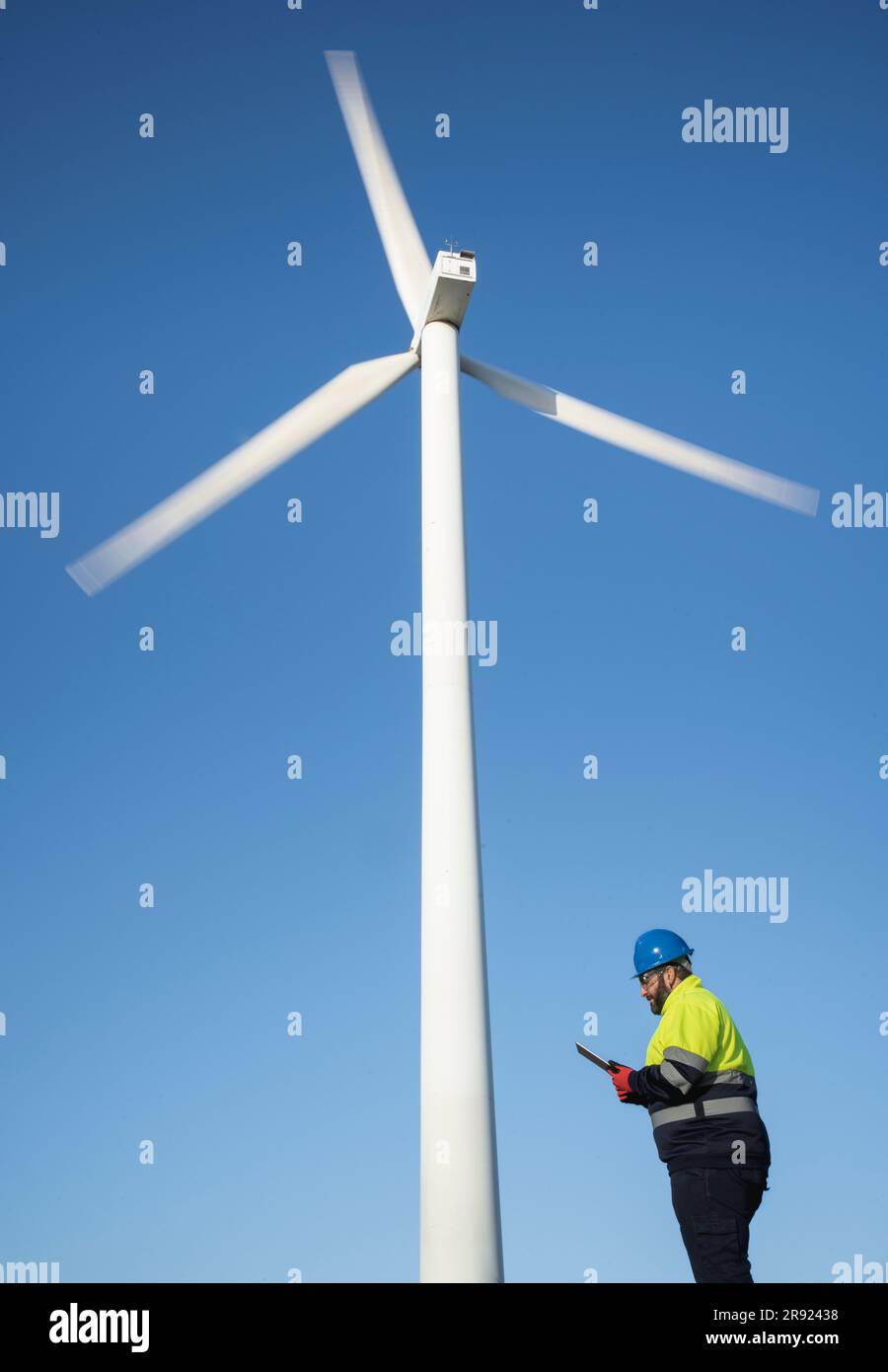 Engineer using tablet PC standing near wind turbine Stock Photo
