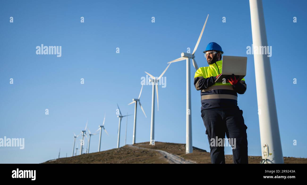 Engineer working on laptop standing at wind park Stock Photo