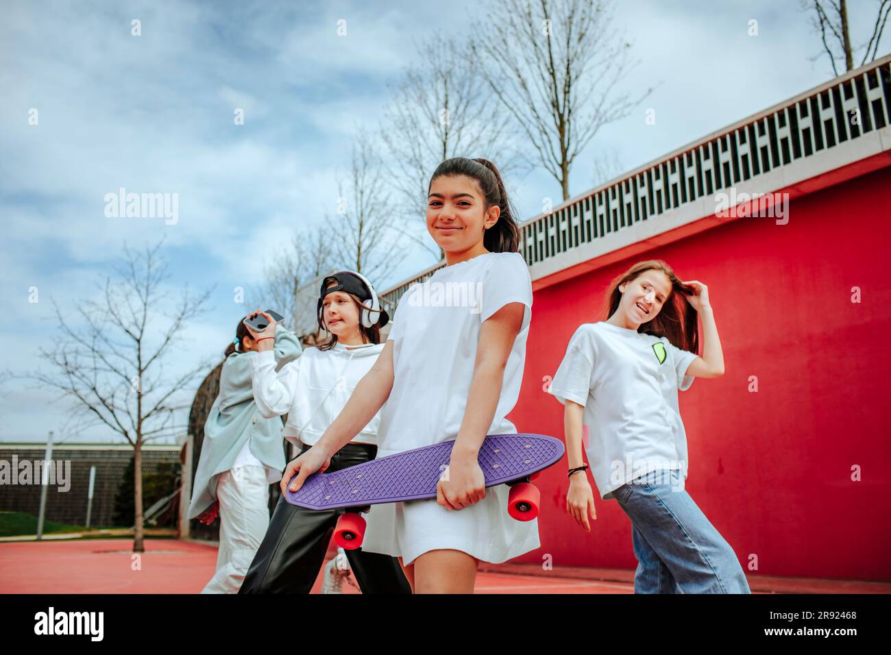 Teenage girl with skateboard spending leisure time at playground Stock Photo