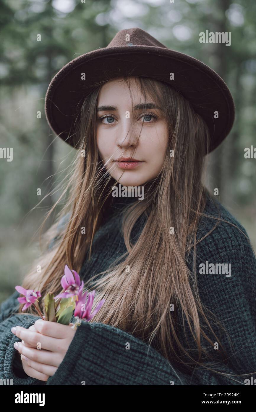 Beautiful young woman with long hair holding flowers Stock Photo