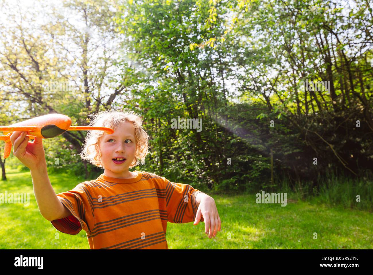 Happy blond boy playing with airplane toy Stock Photo