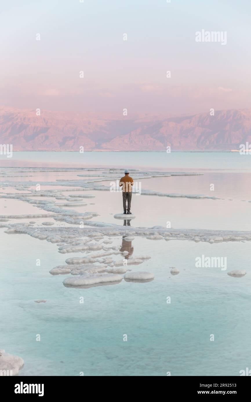 Man standing on salt formations in dead sea Stock Photo