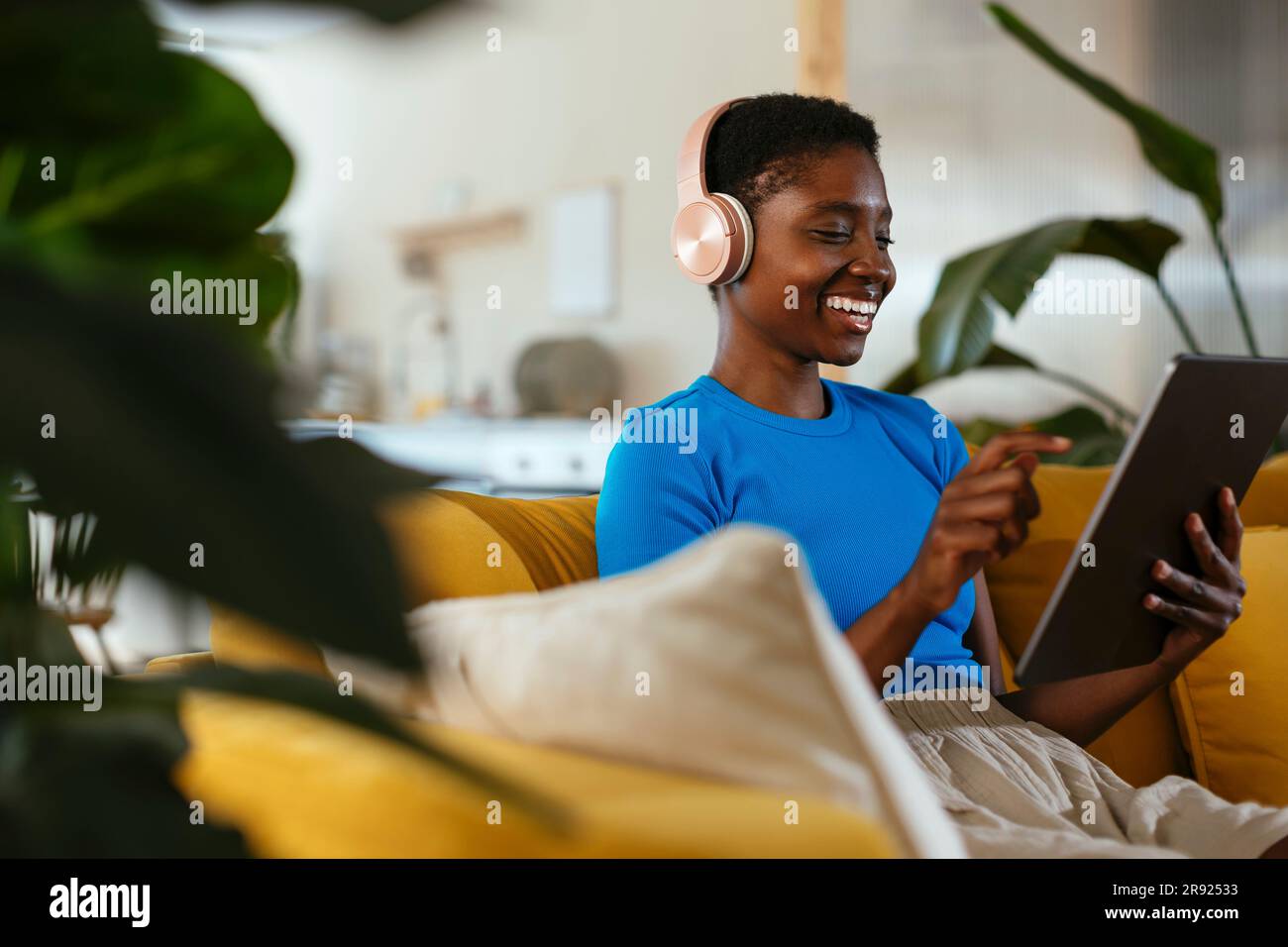 Happy young freelancer using tablet PC on sofa Stock Photo