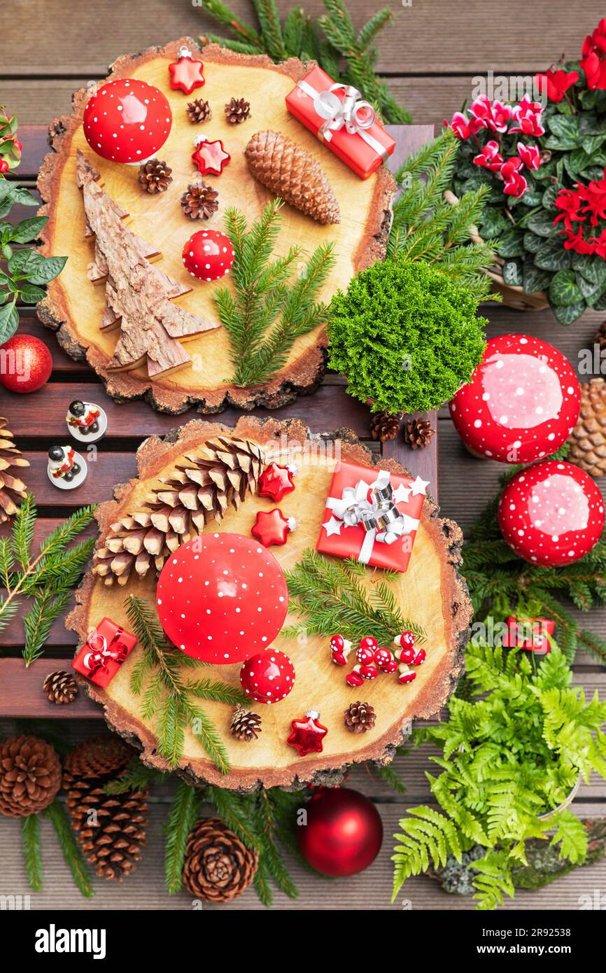 Winter plants, pine cones, Christmas decorations, wooden coasters and presents on table Stock Photo
