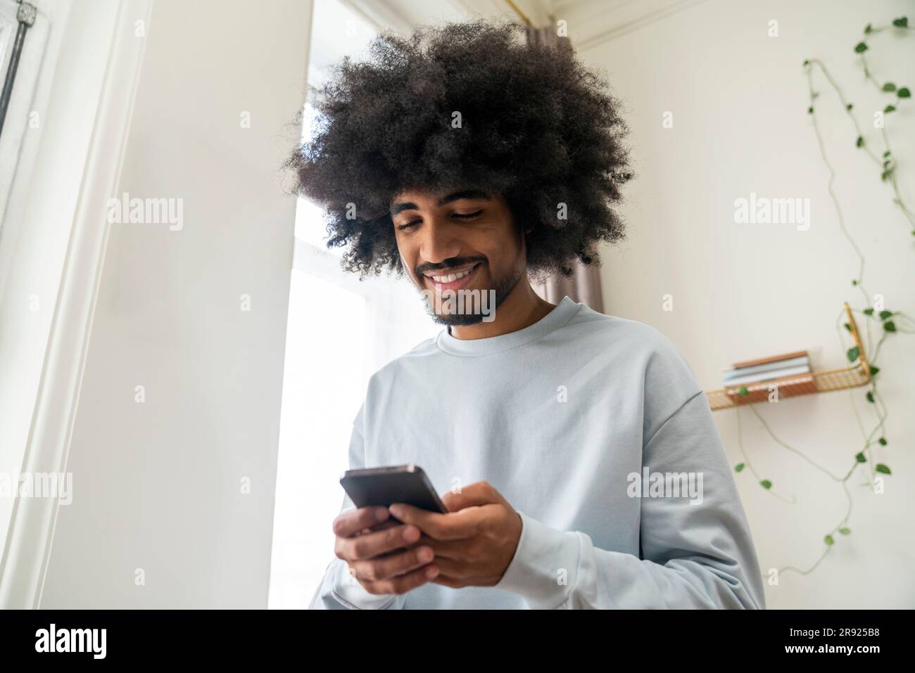 Smiling man using smart phone at home Stock Photo
