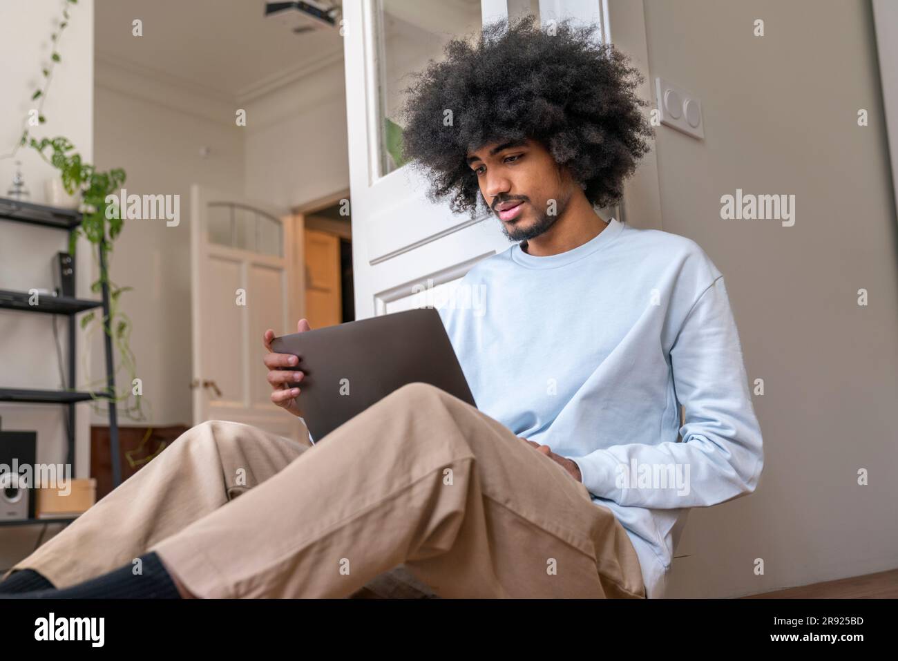 Freelancer working on laptop sitting on floor at home Stock Photo