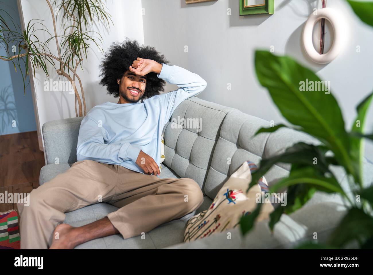 Smiling man sitting on sofa at home Stock Photo