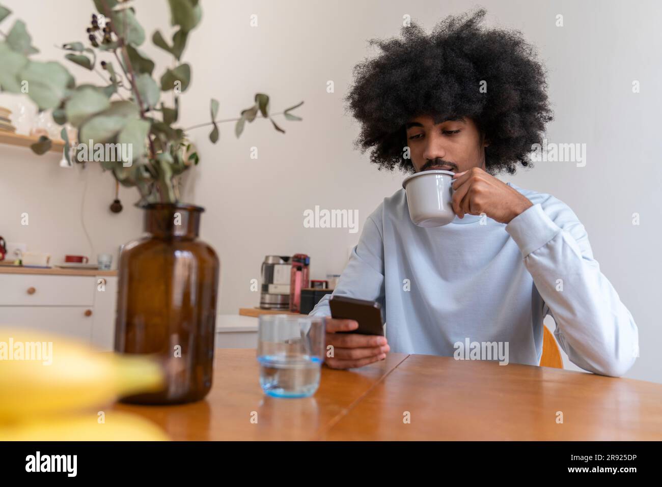 Man drinking coffee and using smart phone at home Stock Photo