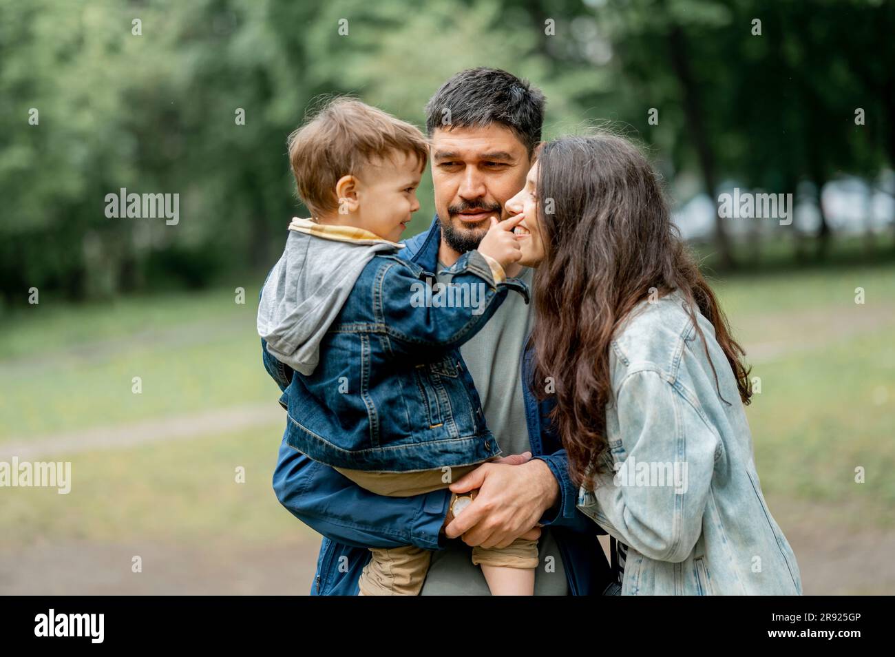 Happy boy touching face of mother in public park Stock Photo