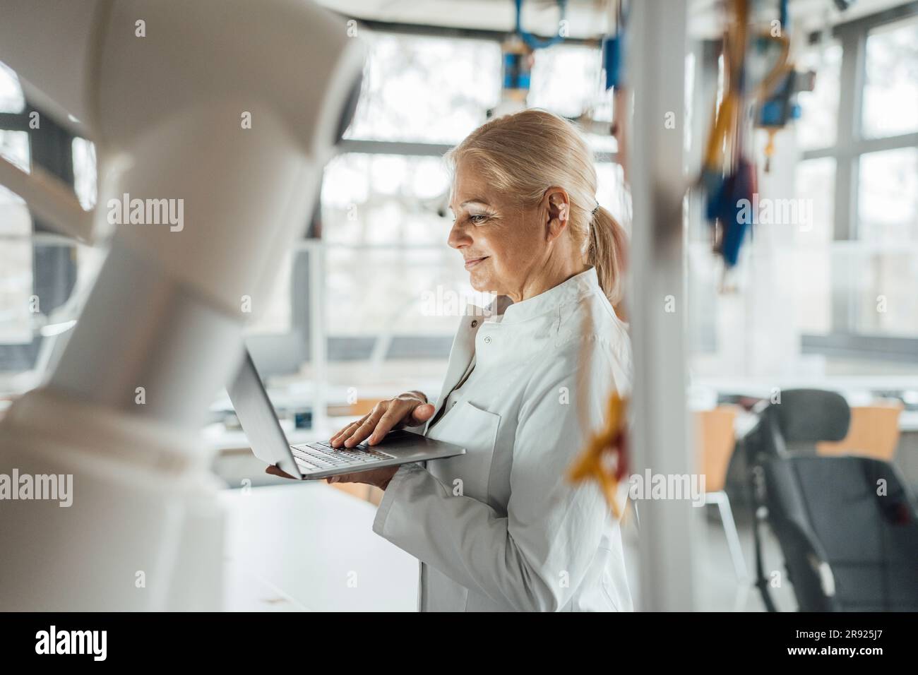 Smiling senior scientist using laptop in laboratory Stock Photo
