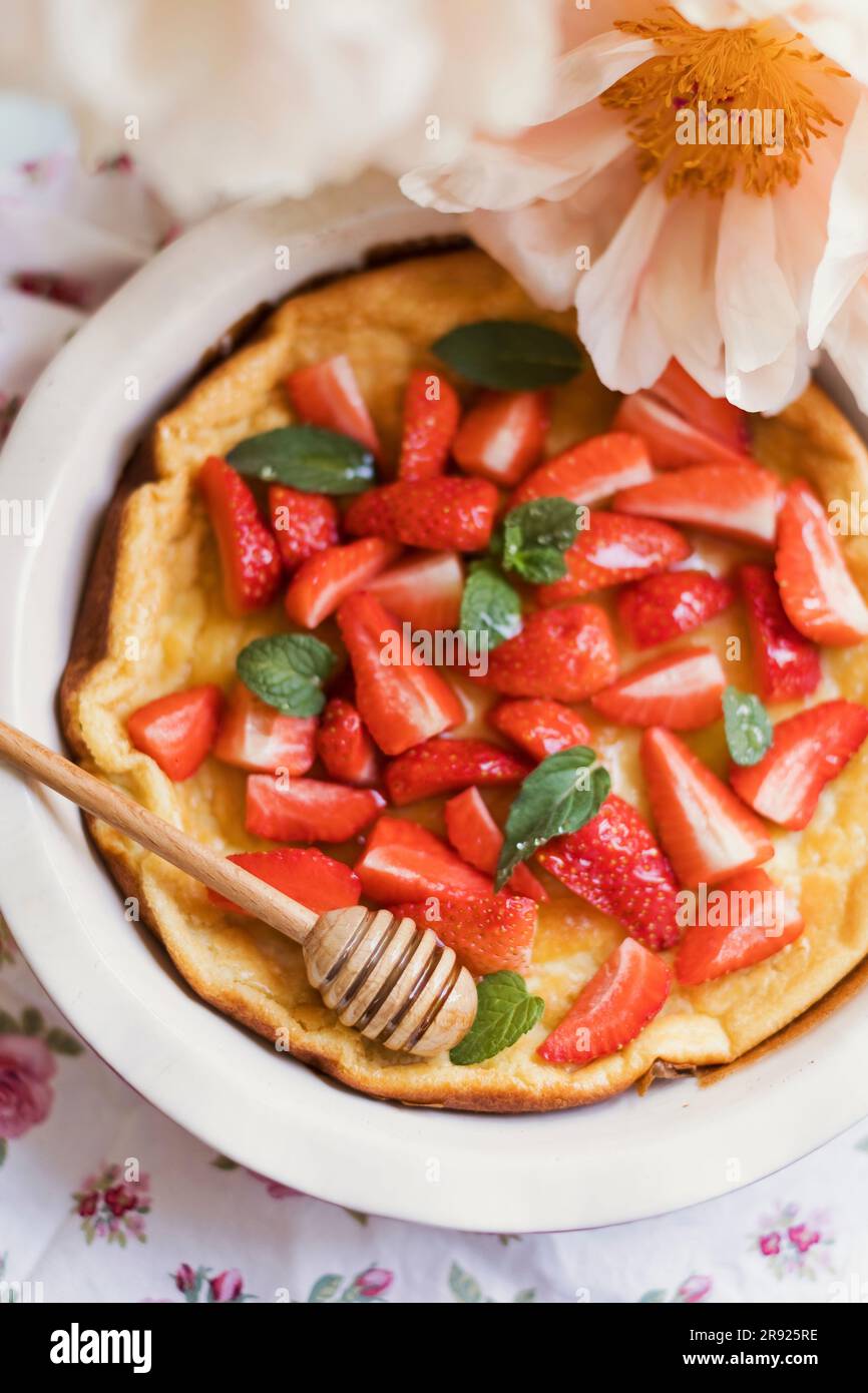 Dutch baby pancake with strawberries, honey and mint Stock Photo