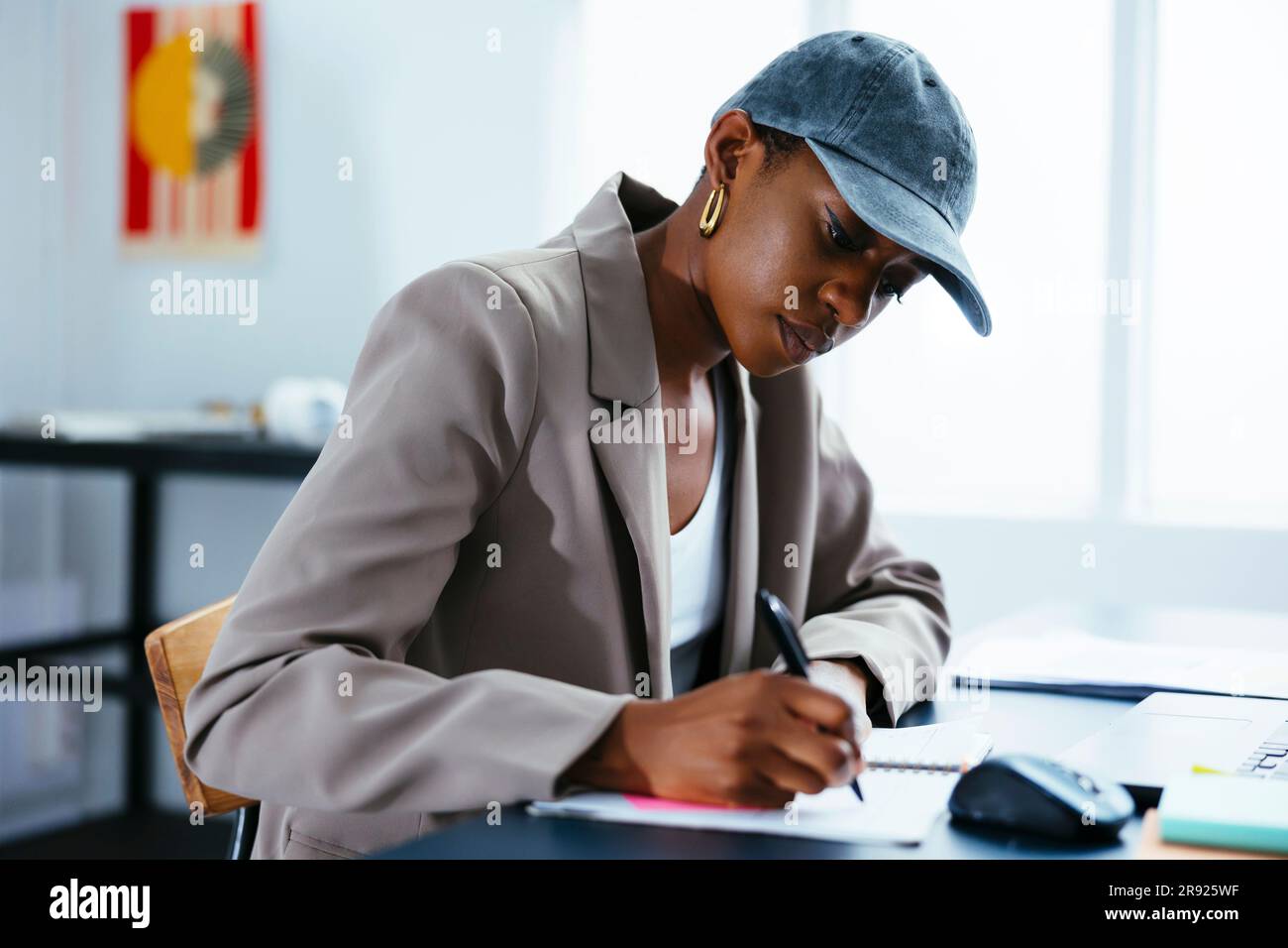 Freelancer wearing cap taking down notes at office Stock Photo