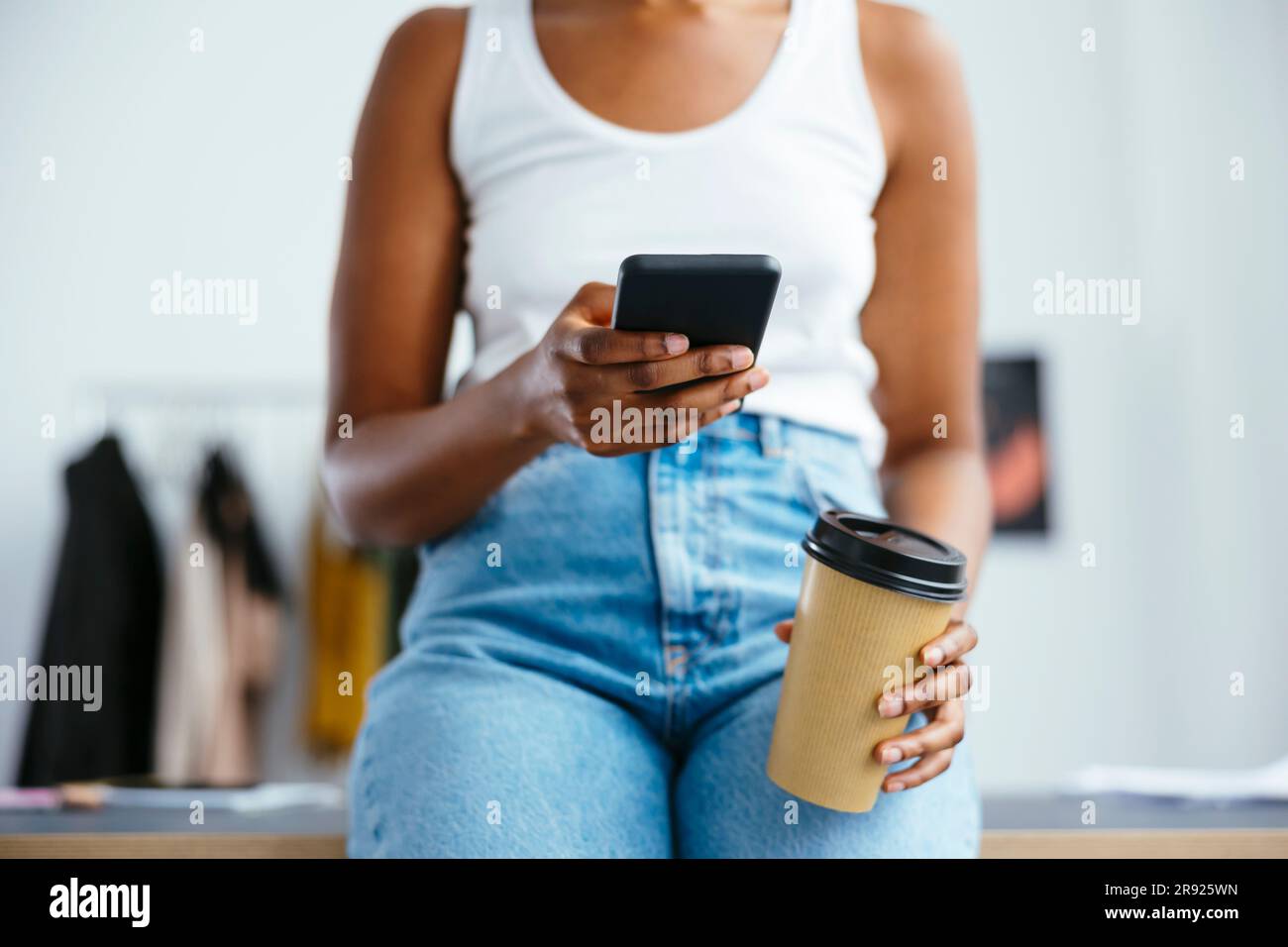 Freelancer using smart phone holding disposable coffee cup Stock Photo