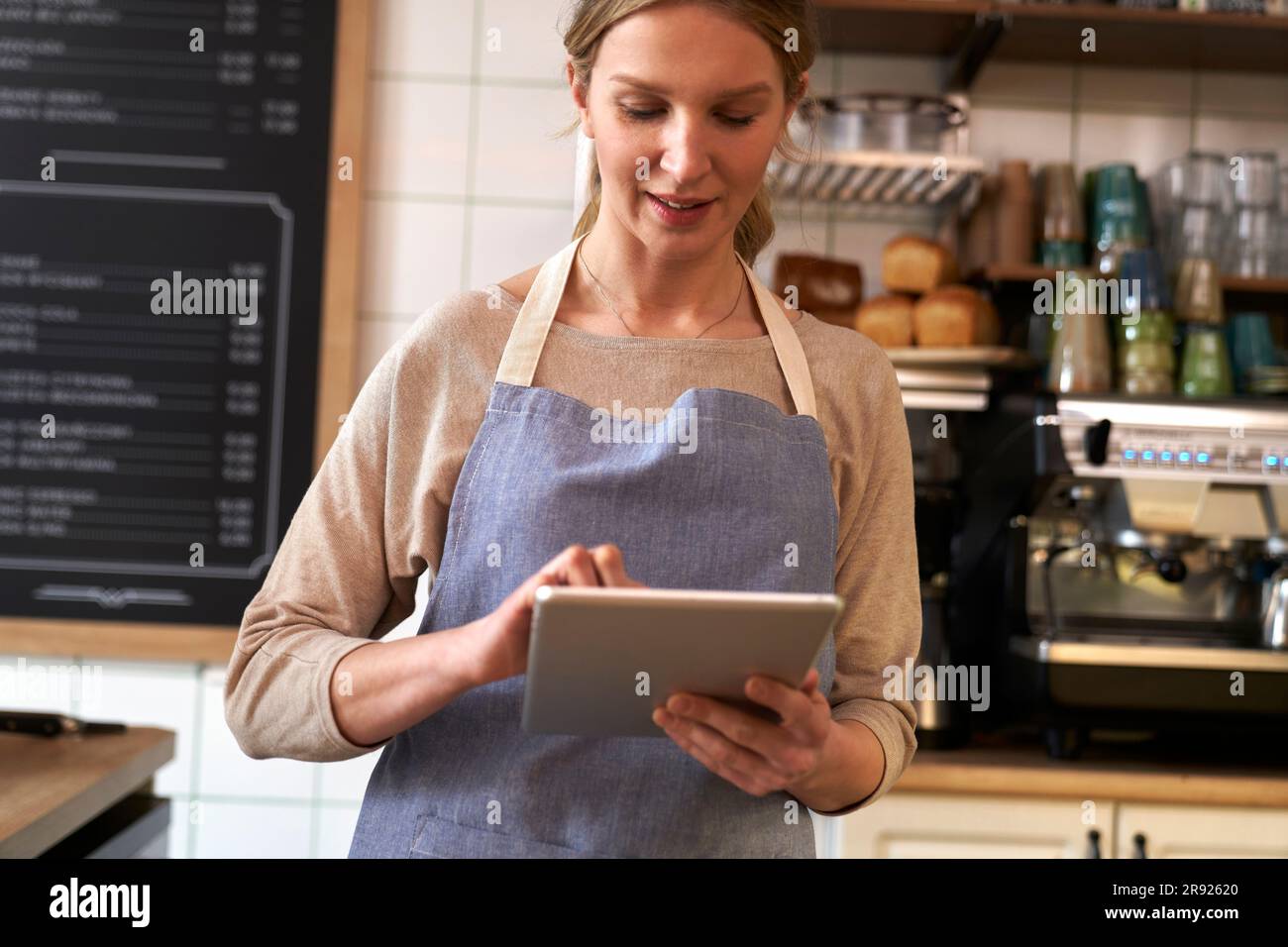 Coffee shop owner using tablet PC in cafe Stock Photo