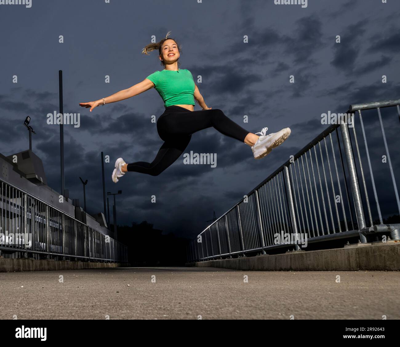 Smiling young athlete jumping on river weir Stock Photo